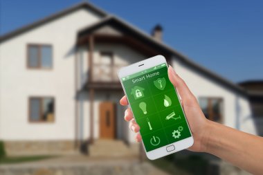 Binanın arka planında ev güvenliği uygulaması olan akıllı telefon.