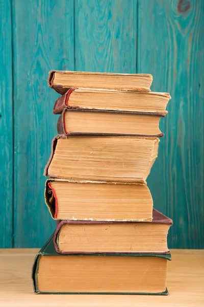 나무 배경 위에 책상 위에 쌓아 놓은 책들 — 스톡 사진