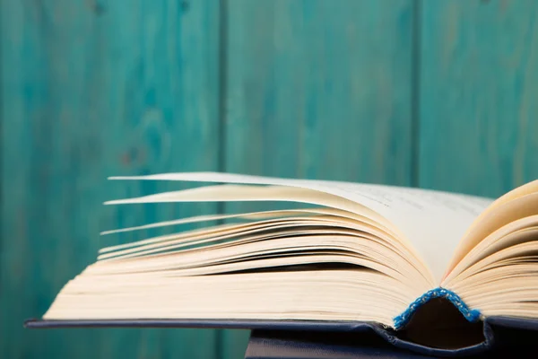 Aufgeschlagenes Buch auf dem Schreibtisch vor Holzgrund — Stockfoto