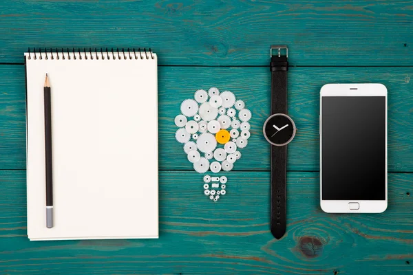 Idea - segno lampadina, blocco note, orologio e telefono sulla scrivania — Foto Stock