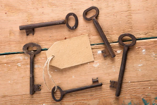 Vecchia chiave arrugginita con etichetta di carta sul pannello di legno — Foto Stock