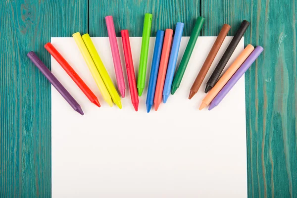 Kolorowe kredki i papier blank na biurku — Zdjęcie stockowe