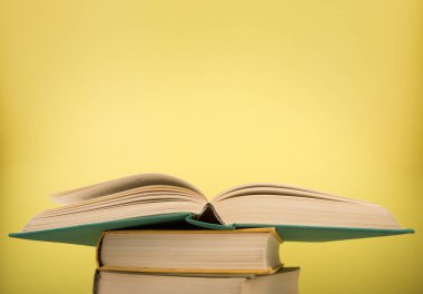 Eğitim ve okuma konsepti - tahta masa üzerinde açık kitap, sarı arkaplan