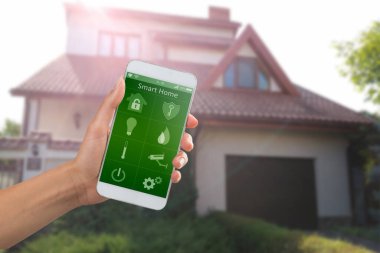 Binanın arka planında ev güvenliği uygulaması olan akıllı telefon.