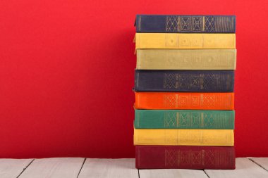 Eğitim ve bilgelik kavramı - ahşap masa üzerinde açık kitap, kırmızı arkaplan