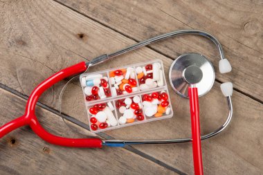 Steteskop ve haplar ahşap masanın üstünde.