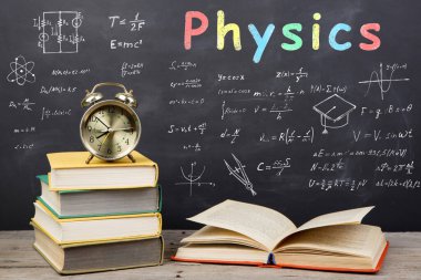 Eğitim kavramı - oditoryumdaki masanın üzerinde kitaplar, formüller ve karatahtadaki fizik yazıları