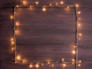 Parti ışıkları süslemesi. Ahşap arkaplan, noel ışıkları çelenk, metin için kopya alanı olan çerçeve