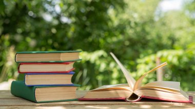 Yaz konseptine çalışıyorum. Güneşli bir yaz gününde, bahçedeki ahşap bir masada açık bir kitap okumak.