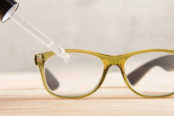 eyesight care concept - eye drops and eyeglasses close up