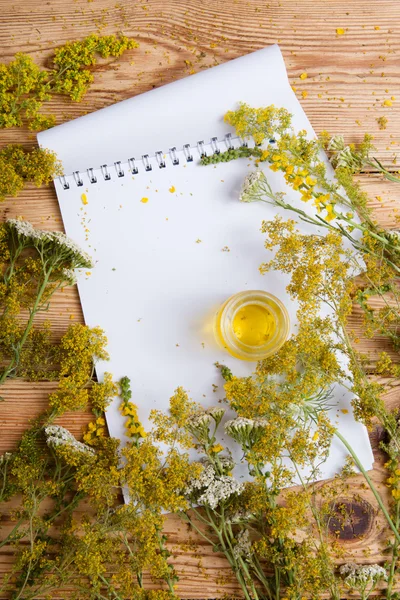 Olio da massaggio in bottiglia di vetro e blocco note sul tavolo di legno — Foto Stock