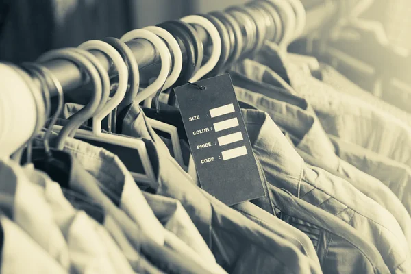 Prázdná cenových etiket na oblečení pověsit na polici v obchodu — Stock fotografie