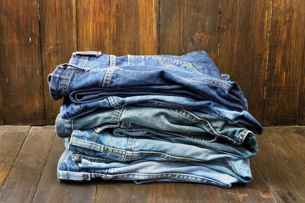 Stack of jeans on wooden background — Stock Photo, Image