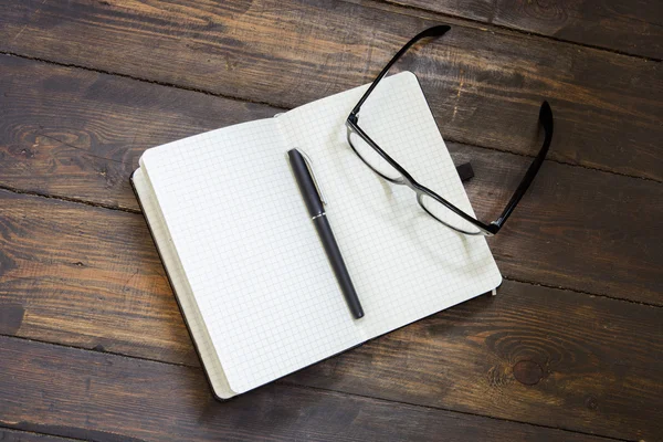 Lectura de gafas y bloc de notas sobre fondo de madera — Foto de Stock