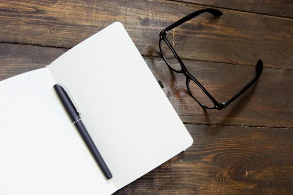 Lectura de gafas y bloc de notas sobre fondo de madera — Foto de Stock