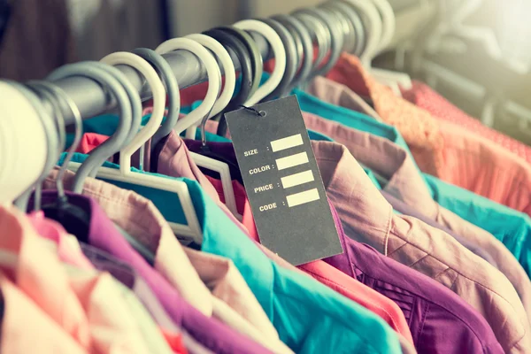 Etiqueta de precio en blanco en la ropa cuelga en un estante en una tienda de moda — Foto de Stock