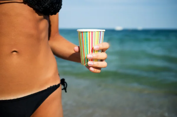 Papper kopp med kaffe i handen på havet bakgrunden — Stockfoto