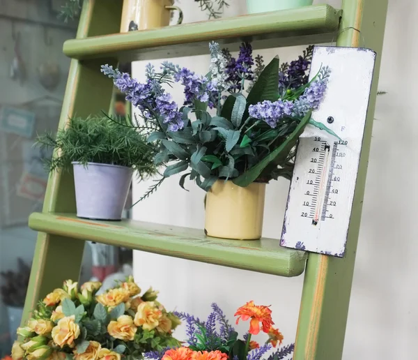 Thermometer en bloemen op oude houten trap — Stockfoto