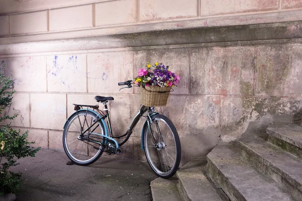 Bicicleta retro con una cesta de flores en la vieja pared — Foto de Stock