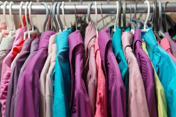 Pakaian tergantung di rak di toko pakaian desainer — Stok Foto