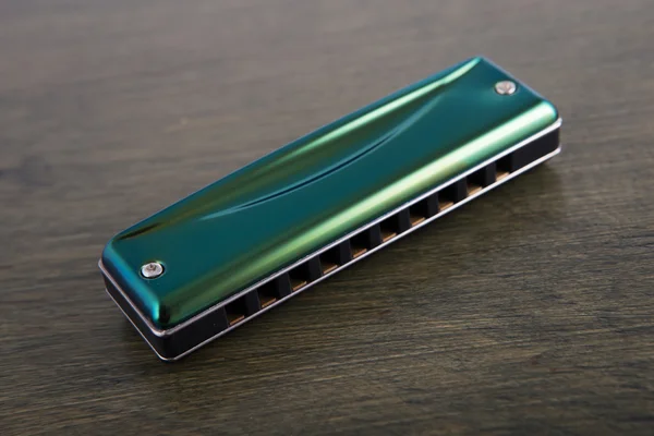 Groene mondharmonica op houten bord — Stockfoto