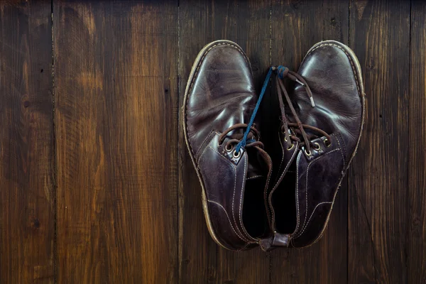 棕色鞋子挂在钉子上木制的背景 — 图库照片