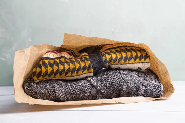 Winkelen voor geschenken - warme truien in een papieren zak op een houten ta — Stockfoto