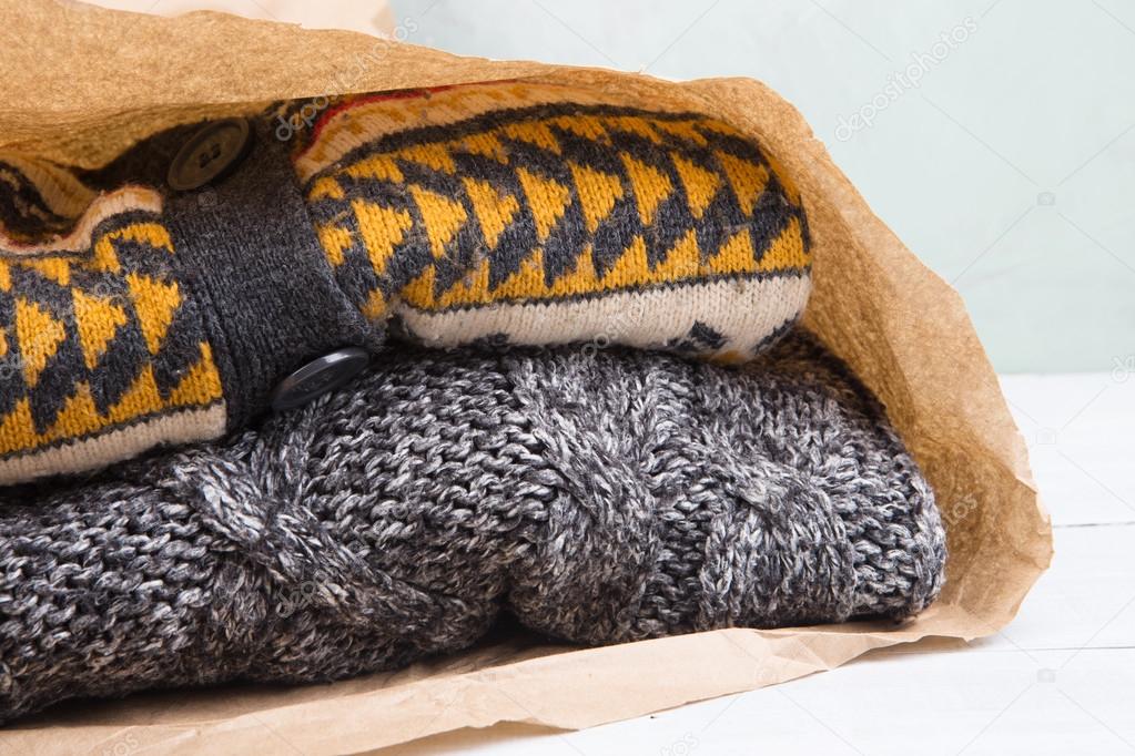 Shopping for gifts - warm sweaters in a paper bag on a wooden ta