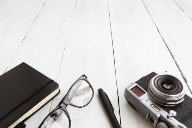 Kamera, Okuma gözlükleri, not defteri ve ahşap arka plan üzerinde tava - 