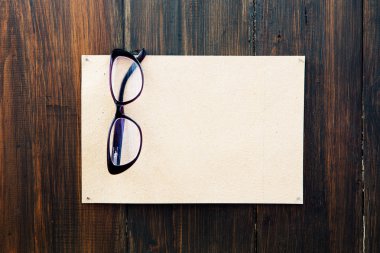 Boş kağıt ve Okuma gözlükleri ahşap duvar üzerinde