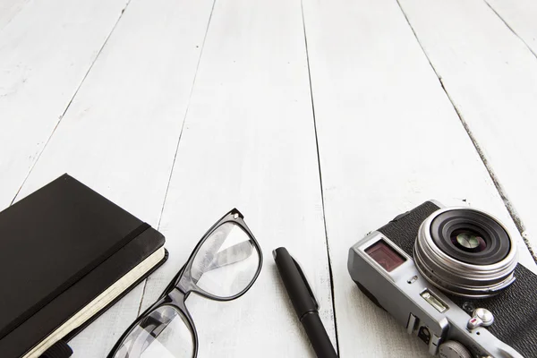 Camera, leesbril, Kladblok en pan op houten achtergrond - — Stockfoto