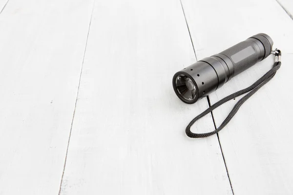 Taschenlampe auf weißem Holzhintergrund — Stockfoto