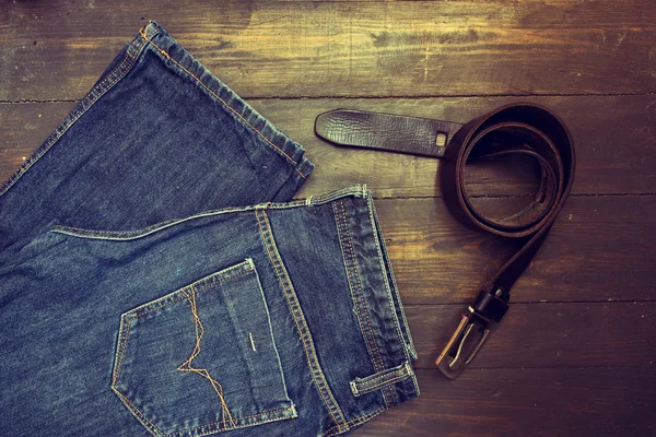 Jeans mit Gürtel auf Holzgrund — Stockfoto