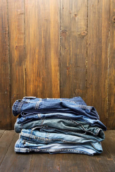 Pilha de jeans no fundo de madeira — Fotografia de Stock