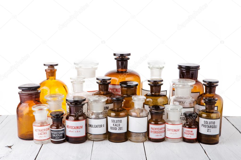 Various vintage pharmacy bottles on wooden table in pharmacy