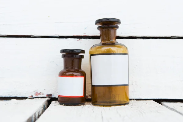 Vintage geneeskundeflessen met etiketten blanco op houten tafel — Stockfoto