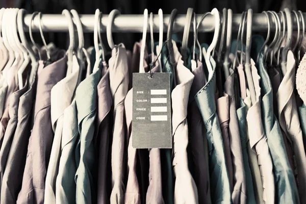 Blank price label on clothes hang on a shelf in a fashion store