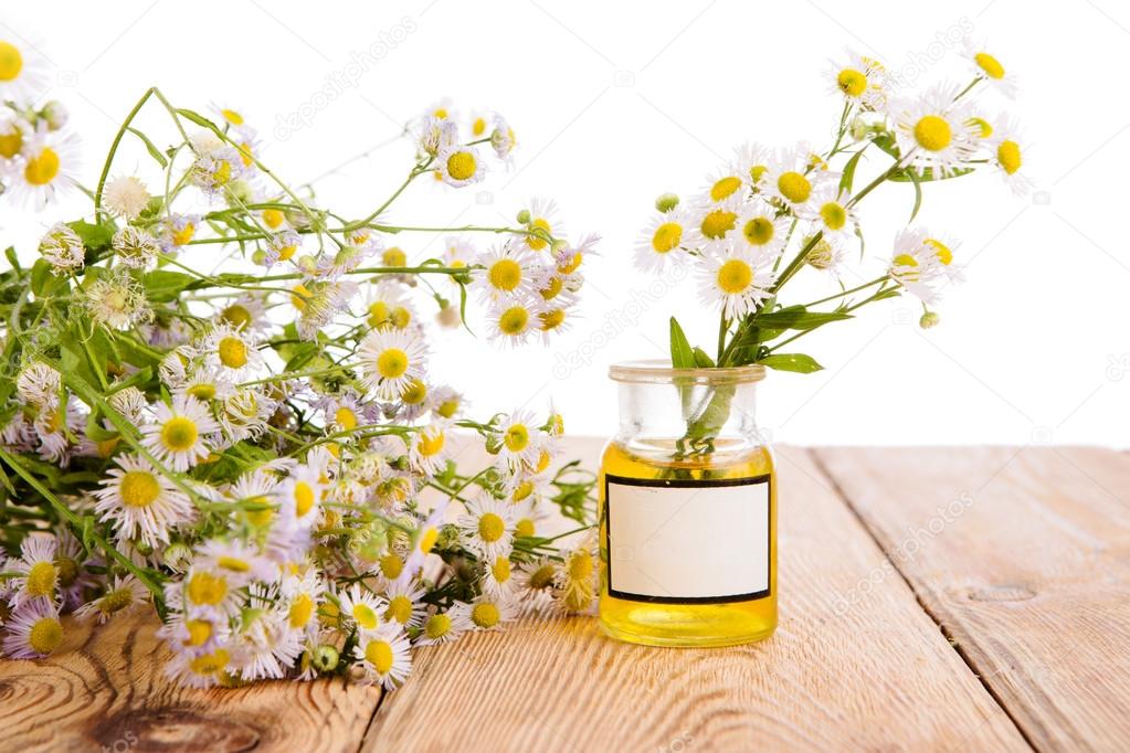 Alternative medicine concept - bottle with camomile on wooden ta