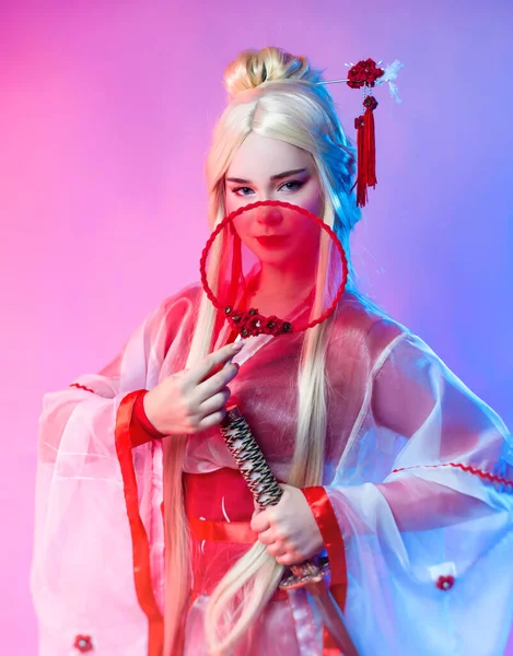 Женщина в костюме гейши с катаной и веером — стоковое фото