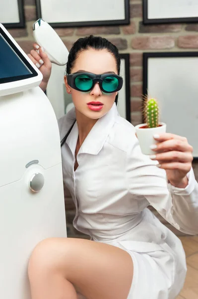 a woman in a laser hair removal Studio poses with a cactus