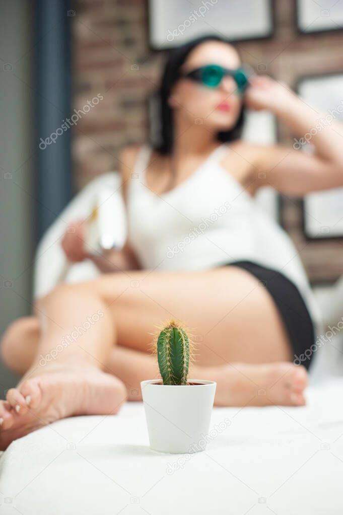 a woman in a laser hair removal Studio poses with a cactus shallow depth of field