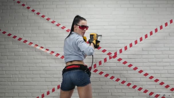 Sexig kvinna i bilden av en byggarbetare i korta shorts som håller en slagskämpe — Stockvideo