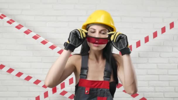 Portrait d'une femme sexy en salopette de construction et un casque enlève ses lunettes — Video