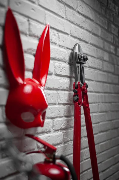 Kreative Gestaltung einer Feuerwand mit Hasenmaske, Feuerlöscher und Bolzenschneider mit gespannter Kette — Stockfoto