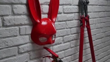 Tavşan maskesi, yangın söndürücü ve esnek zincirli cıvata makası olan bir tuğla duvarın yaratıcı tasarımı.