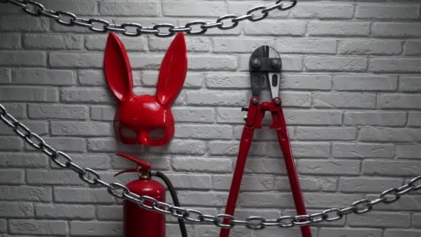 Design creativo di un muro di mattoni di fuoco con una maschera di coniglio, estintori e tagliafuoco con una catena tesa — Video Stock