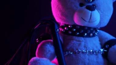 Deri kemer takmış oyuncak ayı BDSM oyunları için aksesuar neon ışıklı karanlık bir arka planda