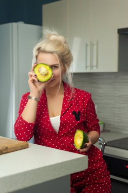 Sarışın vejetaryen mutfakta avokado tutuyor.