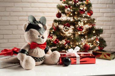 Deri kemer takmış oyuncak ayı Noel ağacının arka planında BDSM için aksesuar.