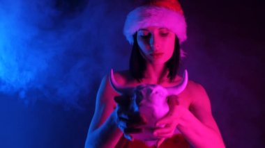 Beyaz boğa heykeli ve neon sisli Noel Baba kılığındaki bir kadın.